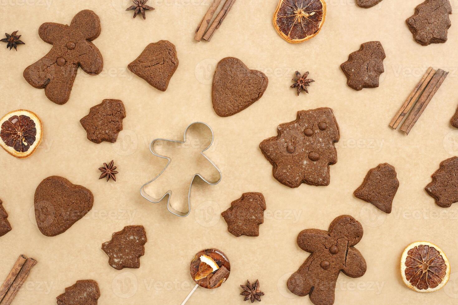 Christmas gingerbread cookies, biscuits, candies and cookie cutter on beige baking paper. Top view minimal pattern, aesthetic flat lay from holiday sweet food, traditional bakery, new year photo