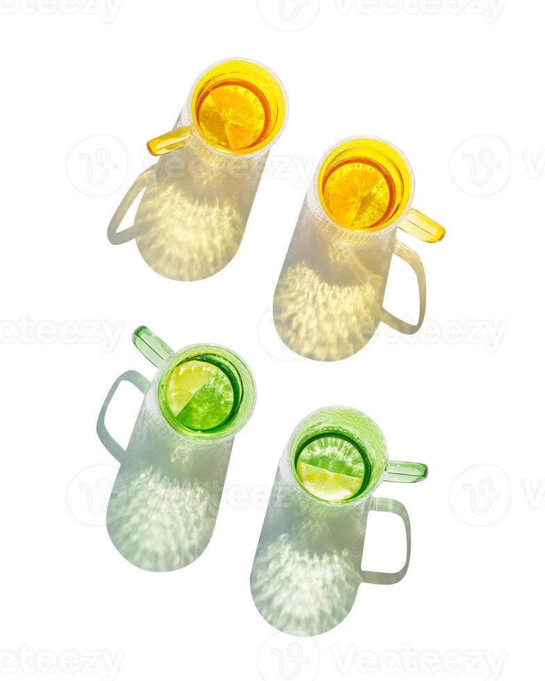 Set Top view colored Glasses of Drinking natural water with slises of lemon, orange, shadow and sunlight reflection isolated white background, Summer drink in yellow green glass cups with handles photo