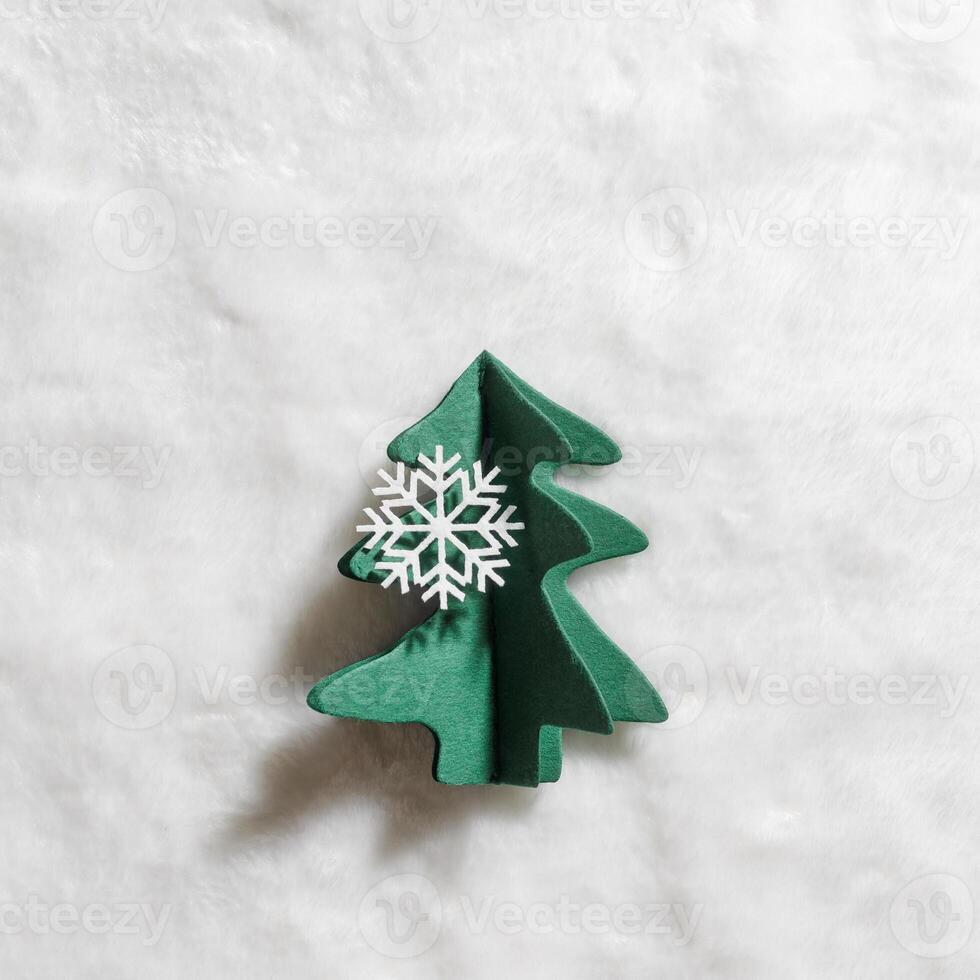 Winter Holidays decoration, Christmas tree of green craft paper, Christmas and New Year minimal style card. Handcraft firs decorated ornamental snowflakes on white fur background. Top view photo