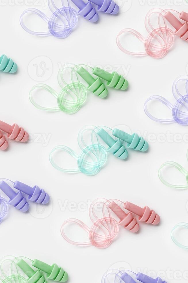Reusable silicone colorful earplugs, for swim, sleep, rest as minimal trend pattern on white background. Soft, flexible ear plug on cord against noise, protect hear, top view, flat lay photo