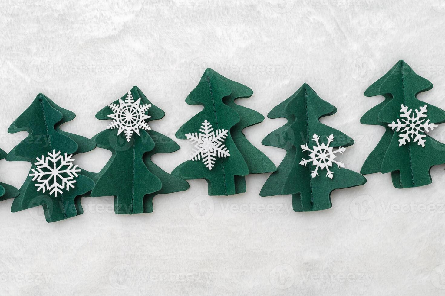 Christmas tree paper cutting, winter holiday background. Handmade origami green fir decorated snowflakes on white fur. Aesthetic top view, minimal flat lay trend pattern, Happy holidays concept photo
