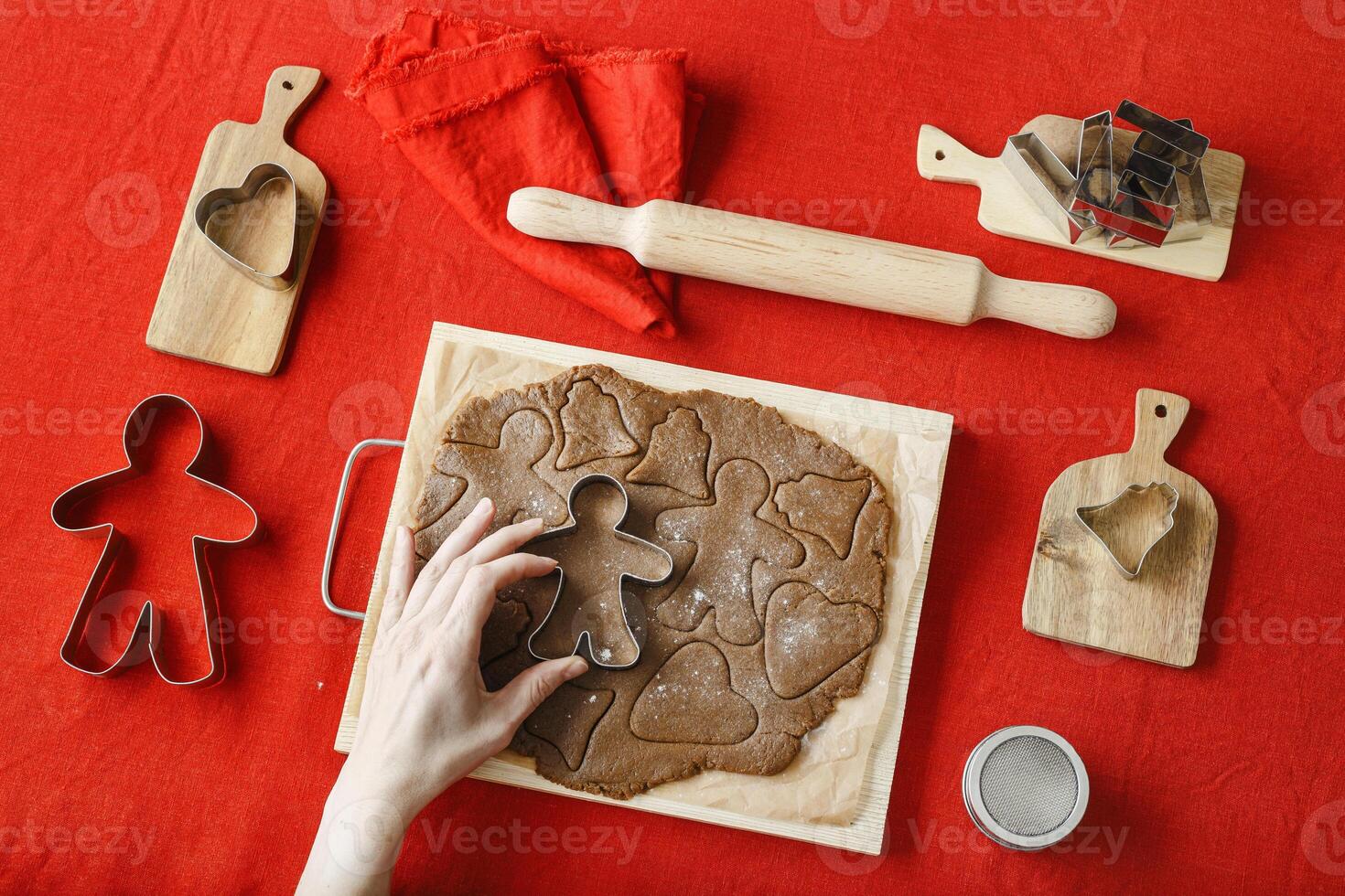 Top view preparing Cooking ginger cookies, Christmas and New Year traditional cookie in shape of gingerbread man, raw rolled out dough, woman hands holding metal pastry cutter on dough photo