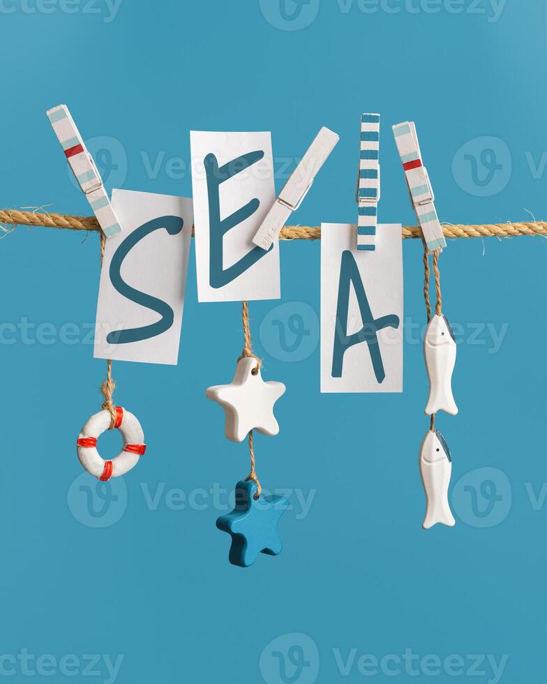 Summer poster with lettering sea on white paper hanging with clothespins on rope. Summer concept in nautical style. photo