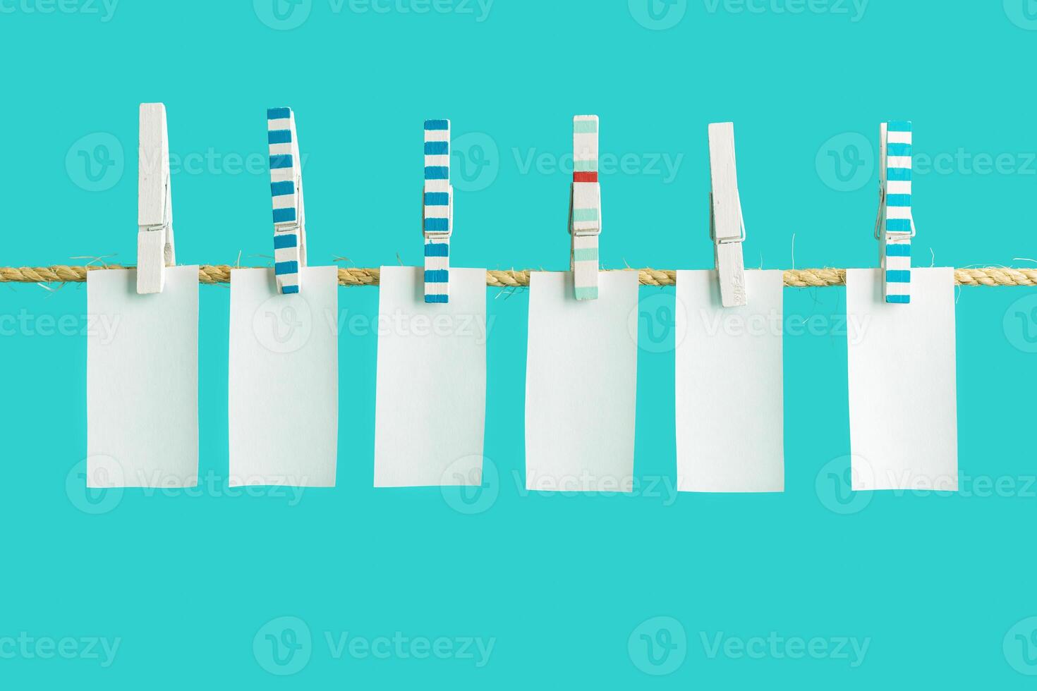 White pieces of paper hang on clothespins on rope, empty space for letters or text. Summer concept photo