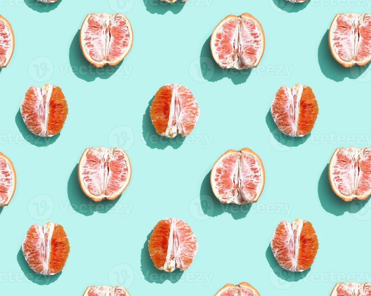 Pattern with red without peel orange or grapefruit on bright turquoise. Minimal summer fruits concept. photo