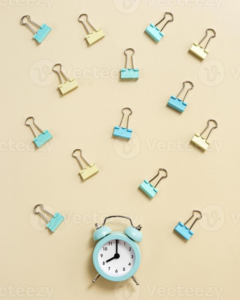 Alarm clock rings at 8 oclock in morning, time to go to school concept. Flat lay with clock and paper clips photo