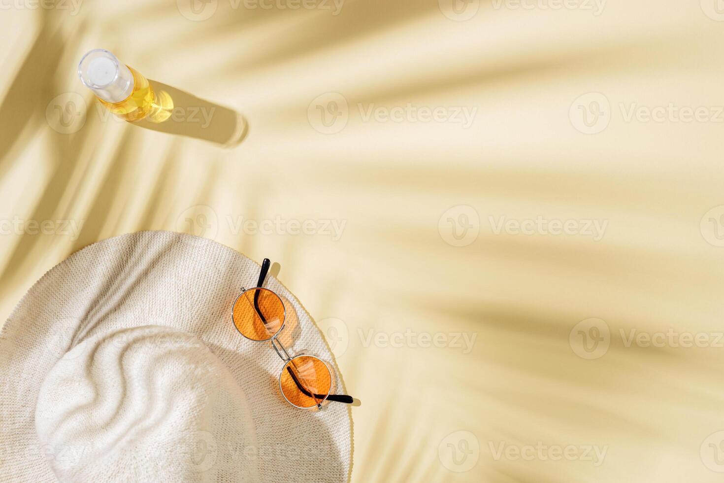 Summer beach rest concept background with sun hat, colored sunglasses, plastic bottle cream with palm tree shadows photo