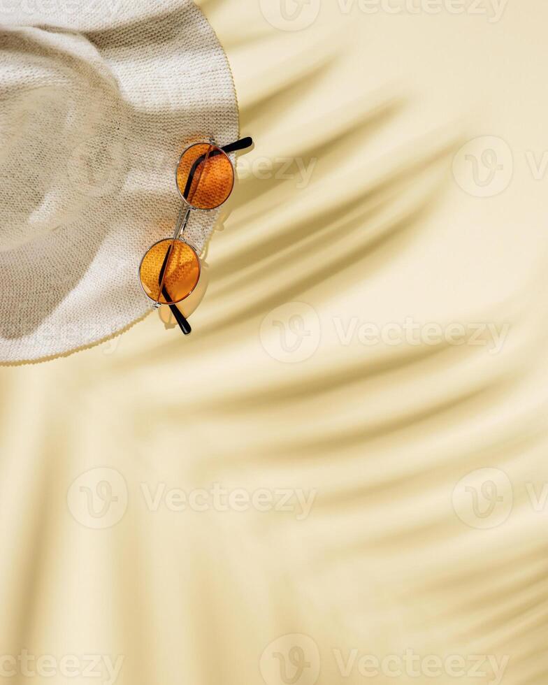 Summer beach rest concept background with hat, colored sunglasses with palm tree shadows. Flat lay with woman accessory photo