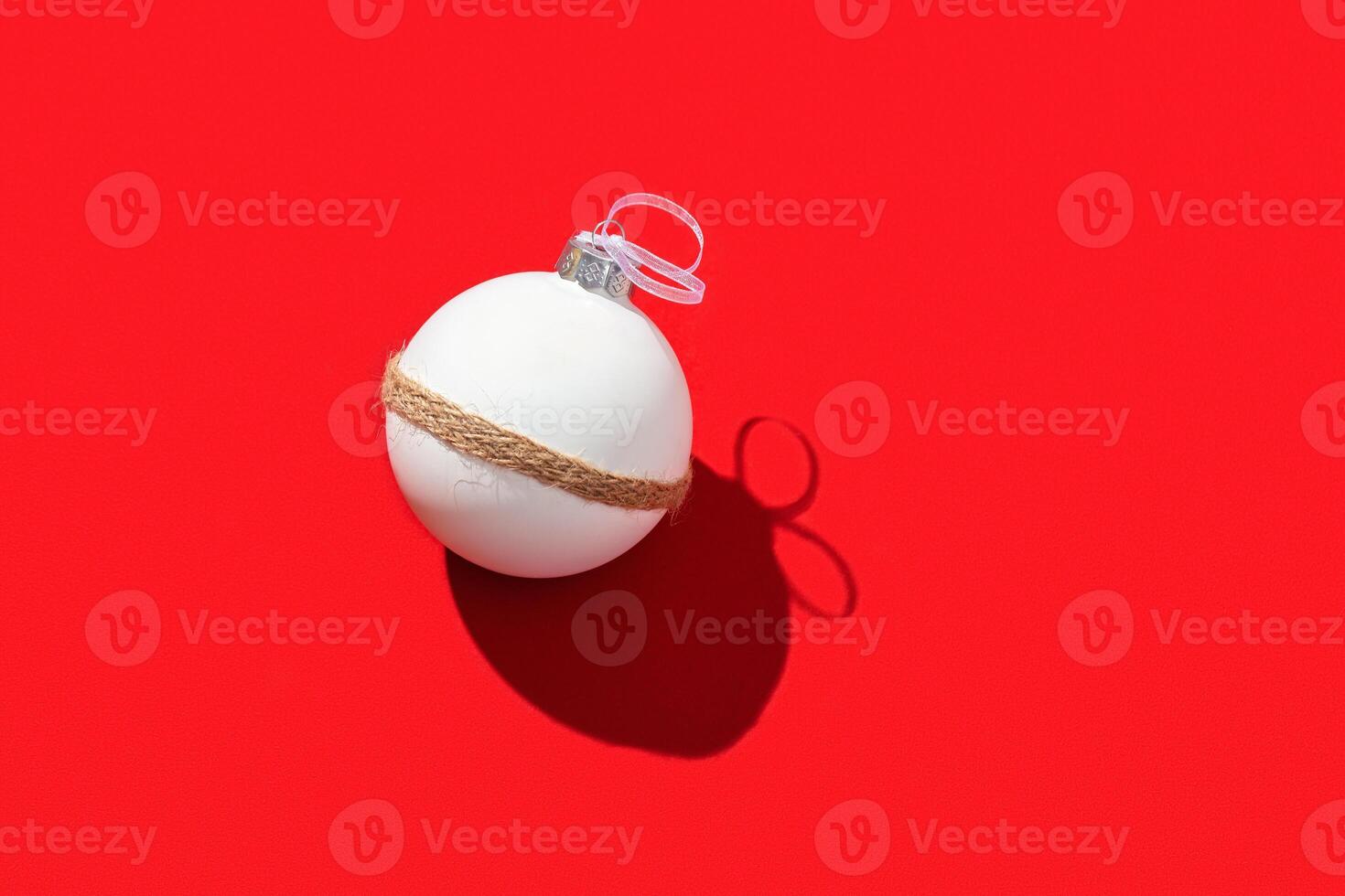 White New years ball, holiday toy on bright red. Christmas greeting card. Minimal style background photo