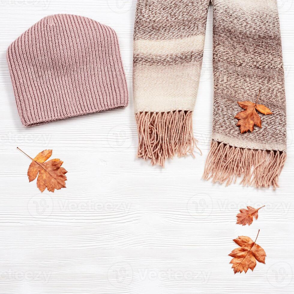 Autumn comfortable clothes and decorative yellow leaves. Scarf and cap for woman photo