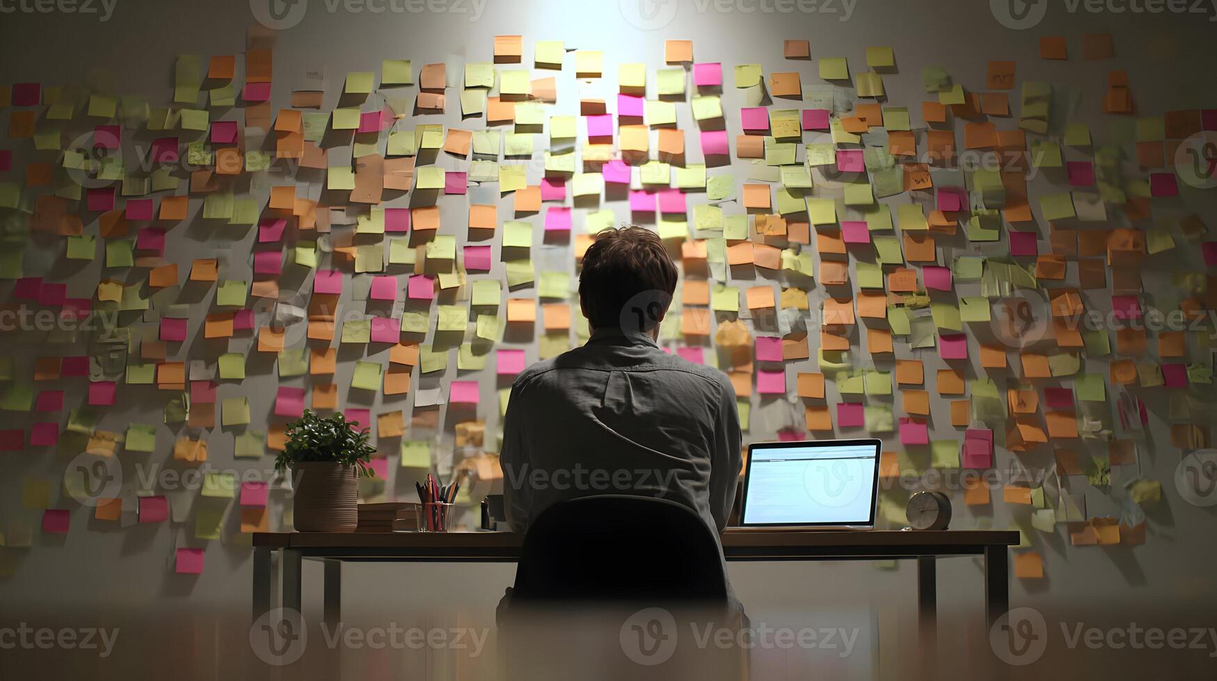Back view of thoughtful man overwhelmed by sticky notes on wall representing complex planning strategy photo