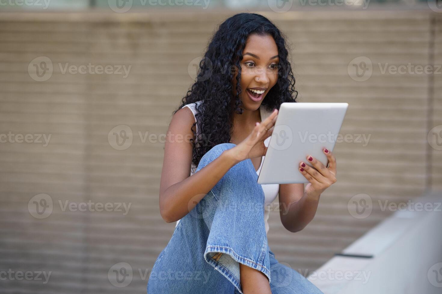 An Excited Young Woman Engaging with a Tablet and Displaying a Joyful Expression on Her Face photo