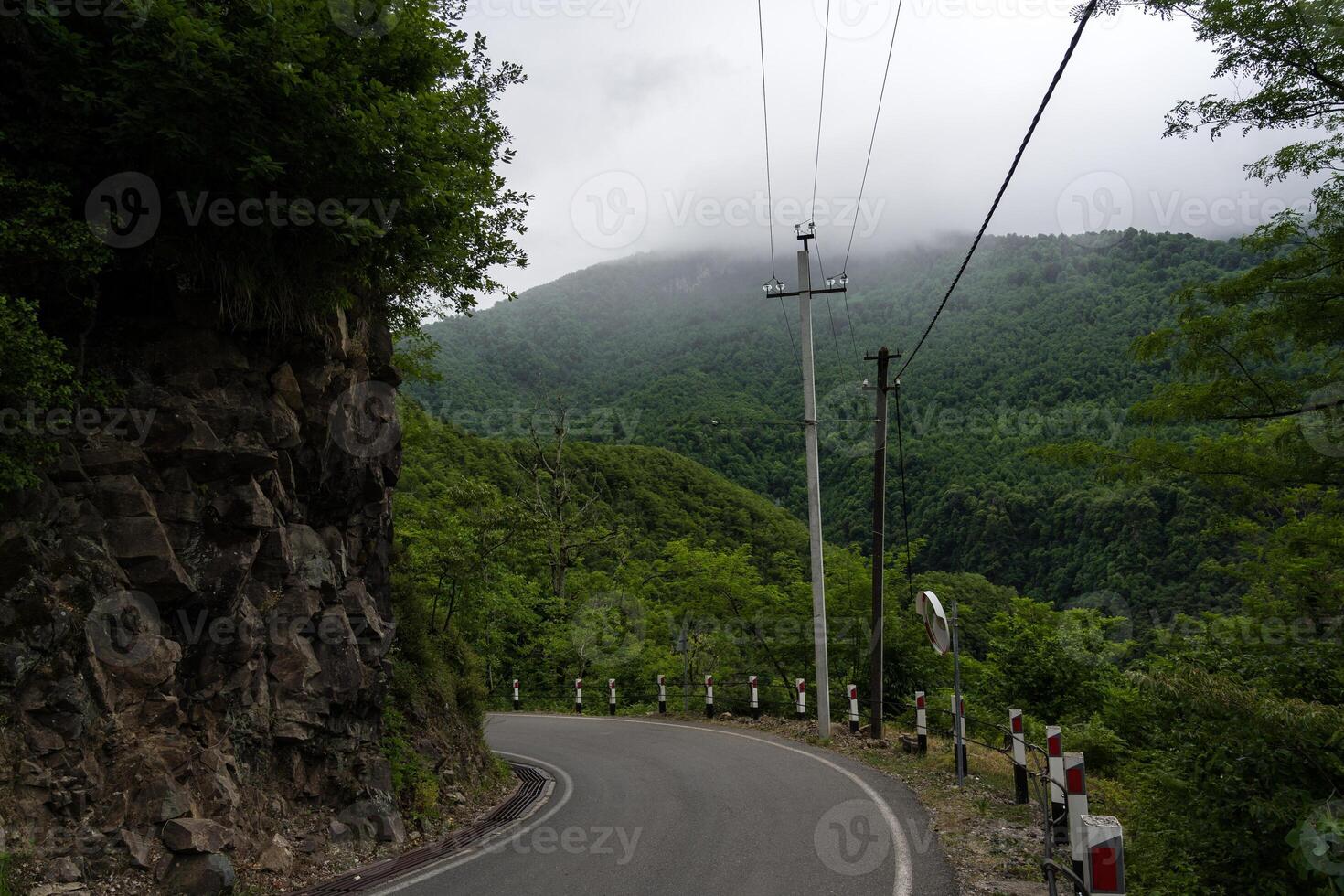 Turn of the road with incredible view of mountains and forest in fog, cloudy photo