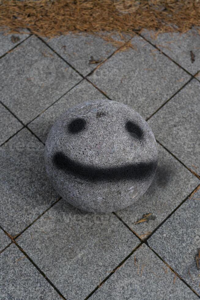 Smile face. stone ball with a face painted on it. Smiley face photo