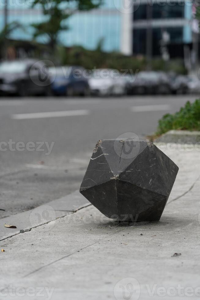 Concrete fence polygonal cube, on the background of the road photo