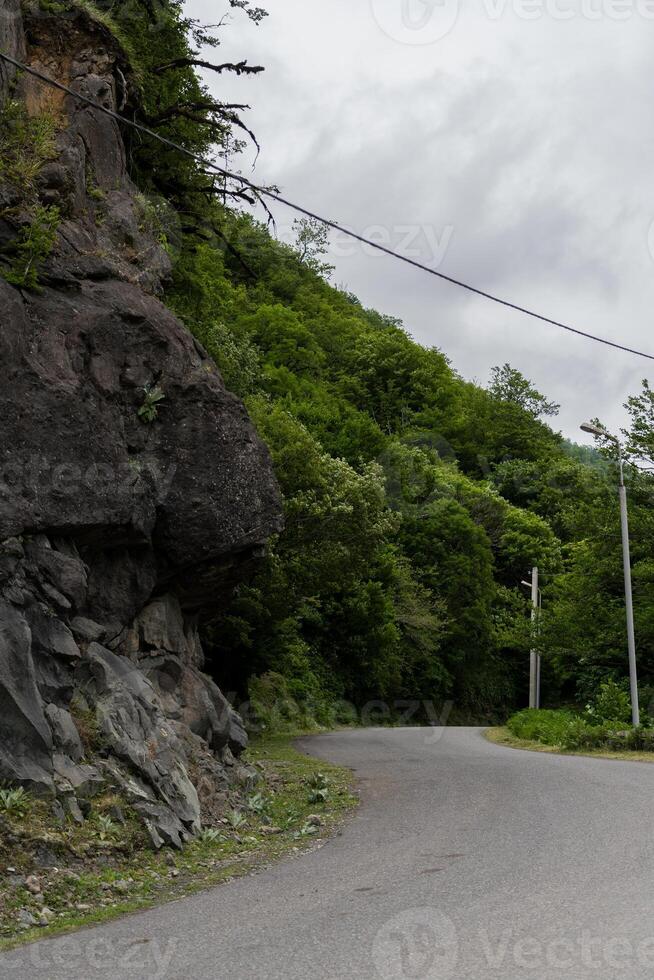 Turn of the road near a cliff on the background of mountains photo