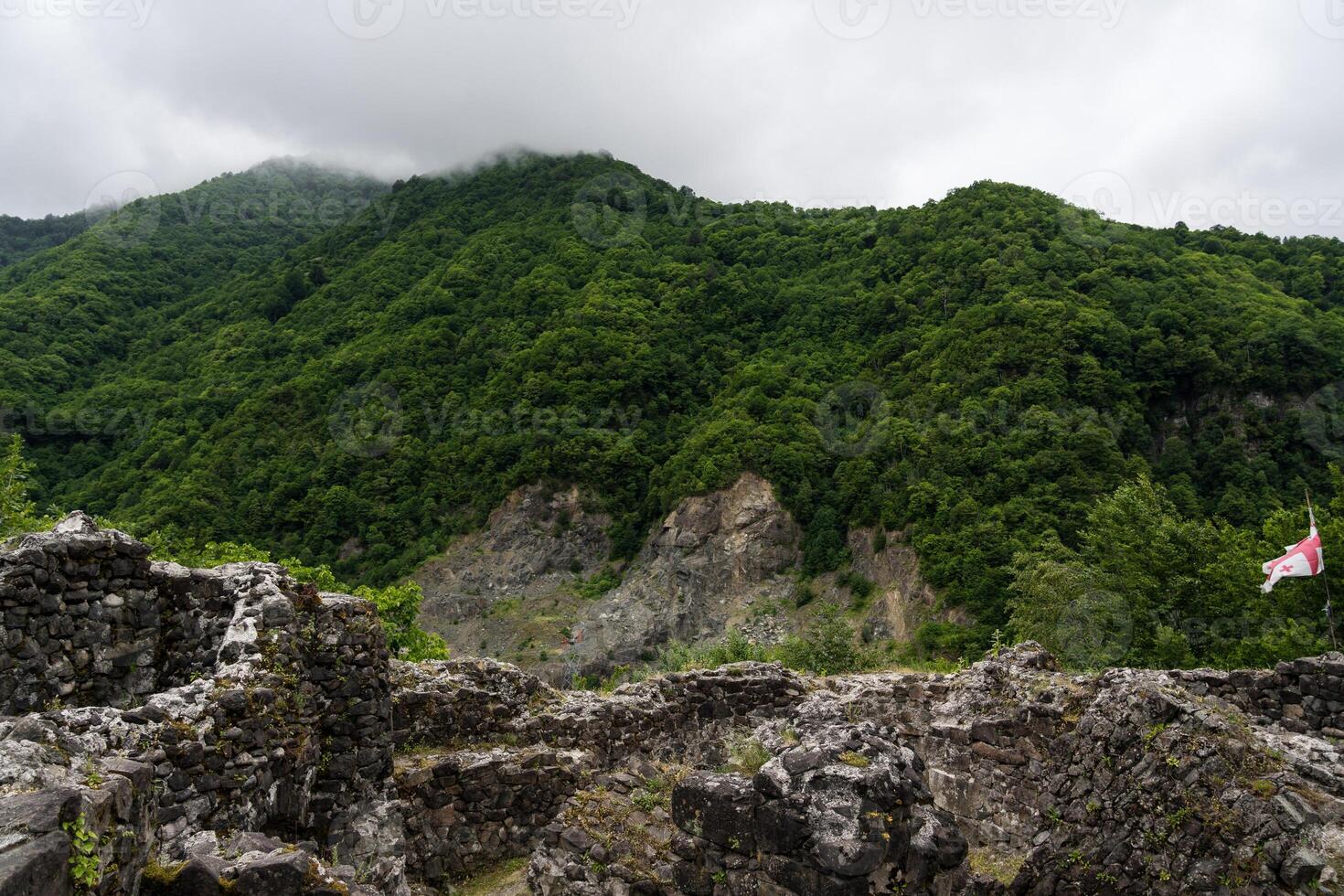The fortress of Gvara against the background of green mountains and cloudy sky photo