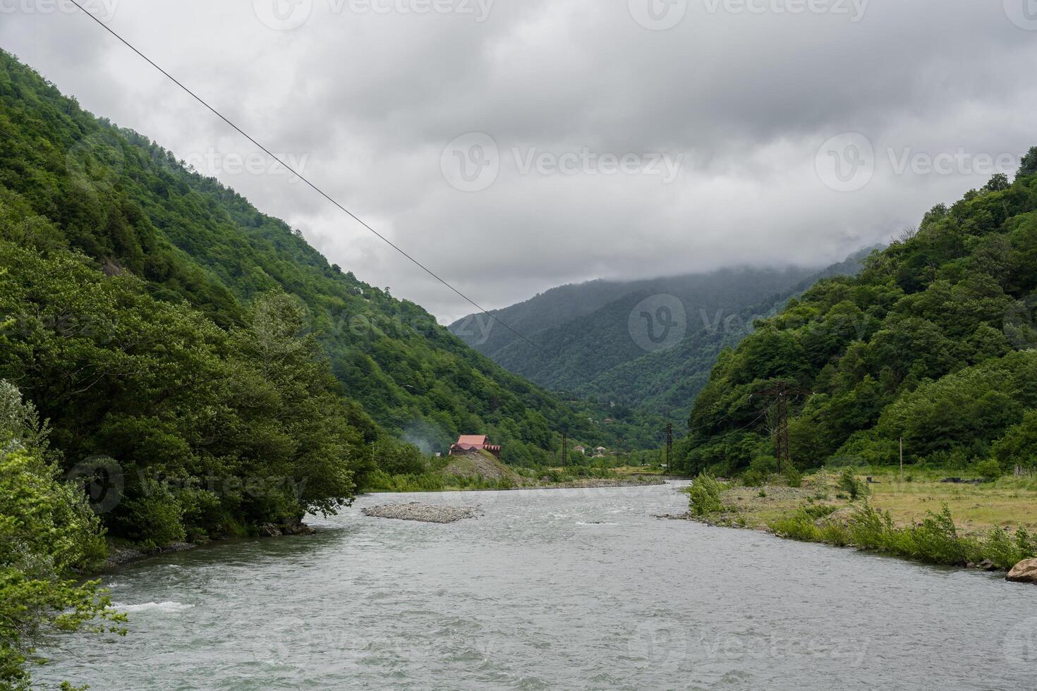 Thick clouds over the mountains, a river between the mountains photo