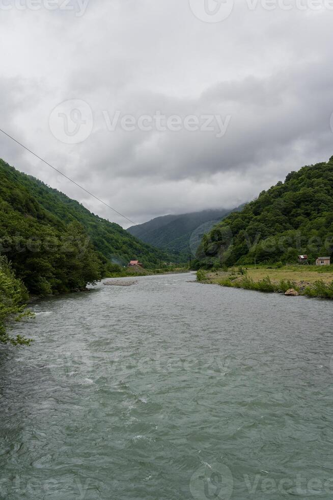 Thick clouds over the mountains a river between the mountains photo