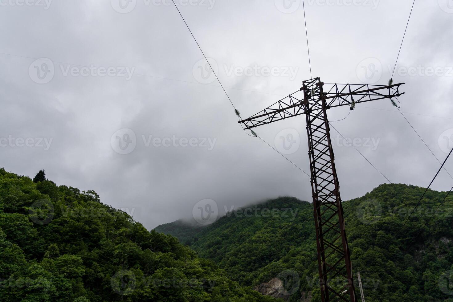 Support of power lines against the background of mountains and thick clouds photo