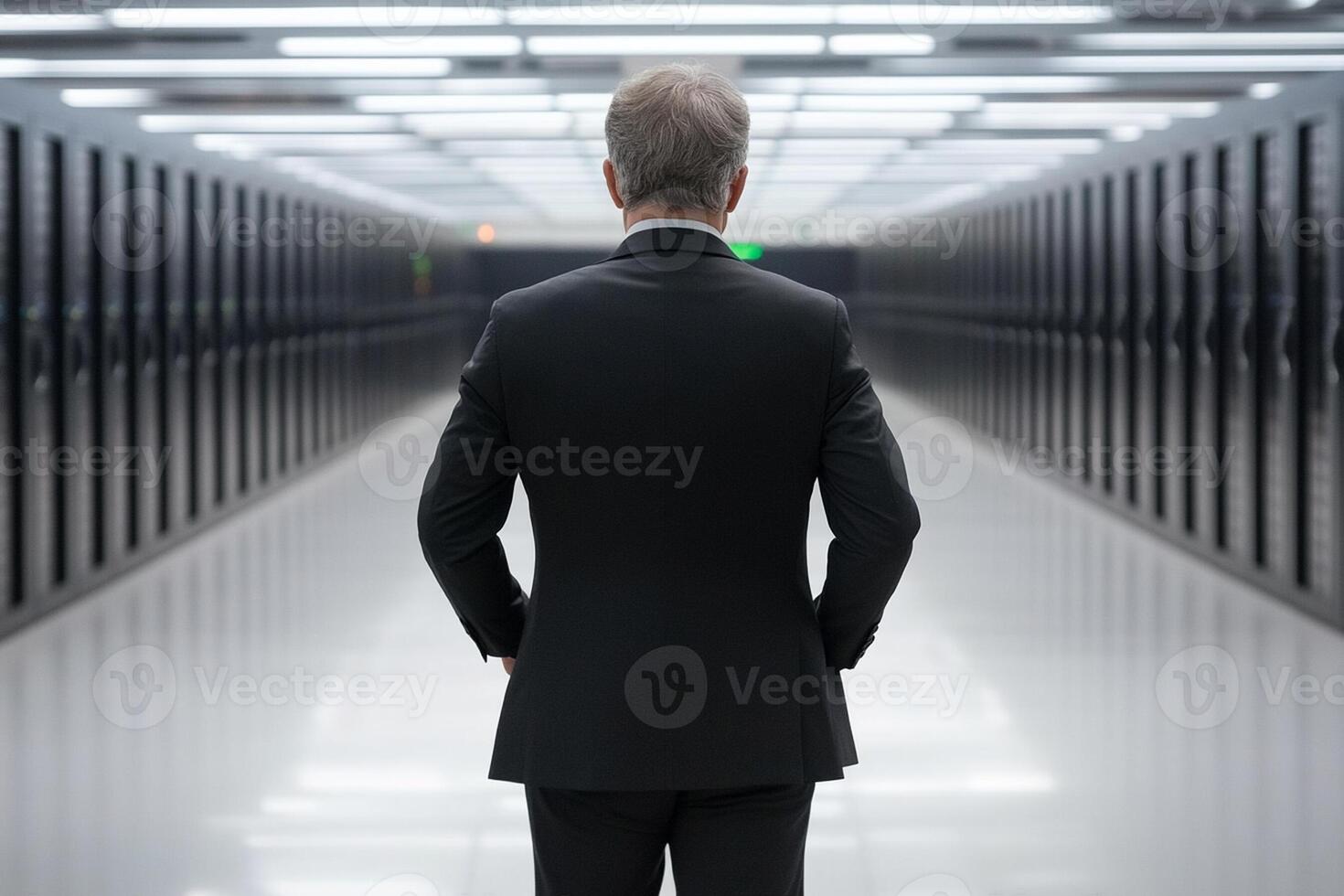 A man in a suit stands in a server room photo