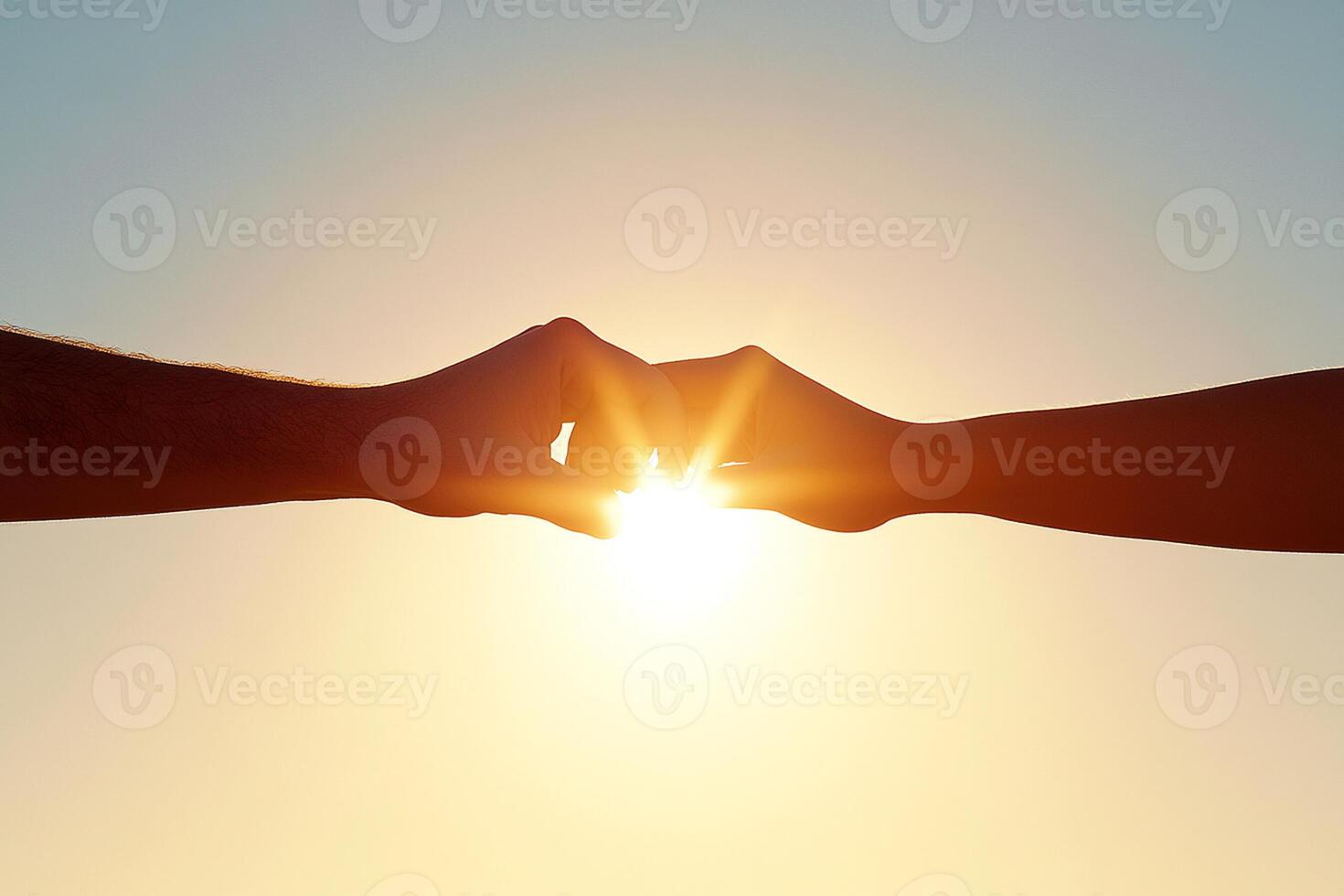 Two hands holding each other in front of the sun photo