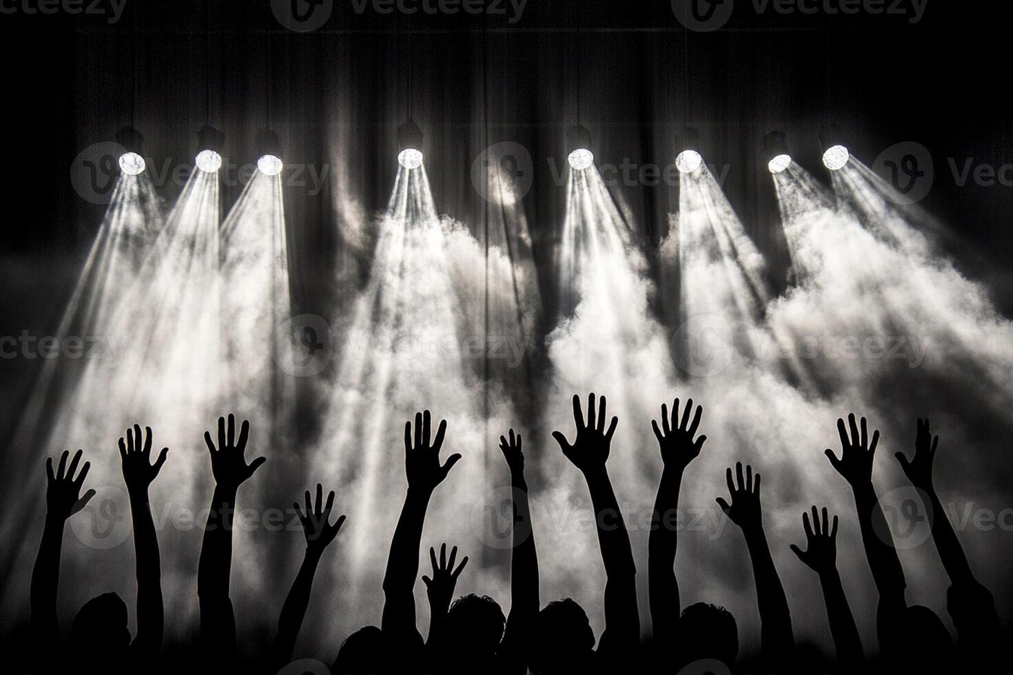 Silhouettes of hands raised in front of a stage photo