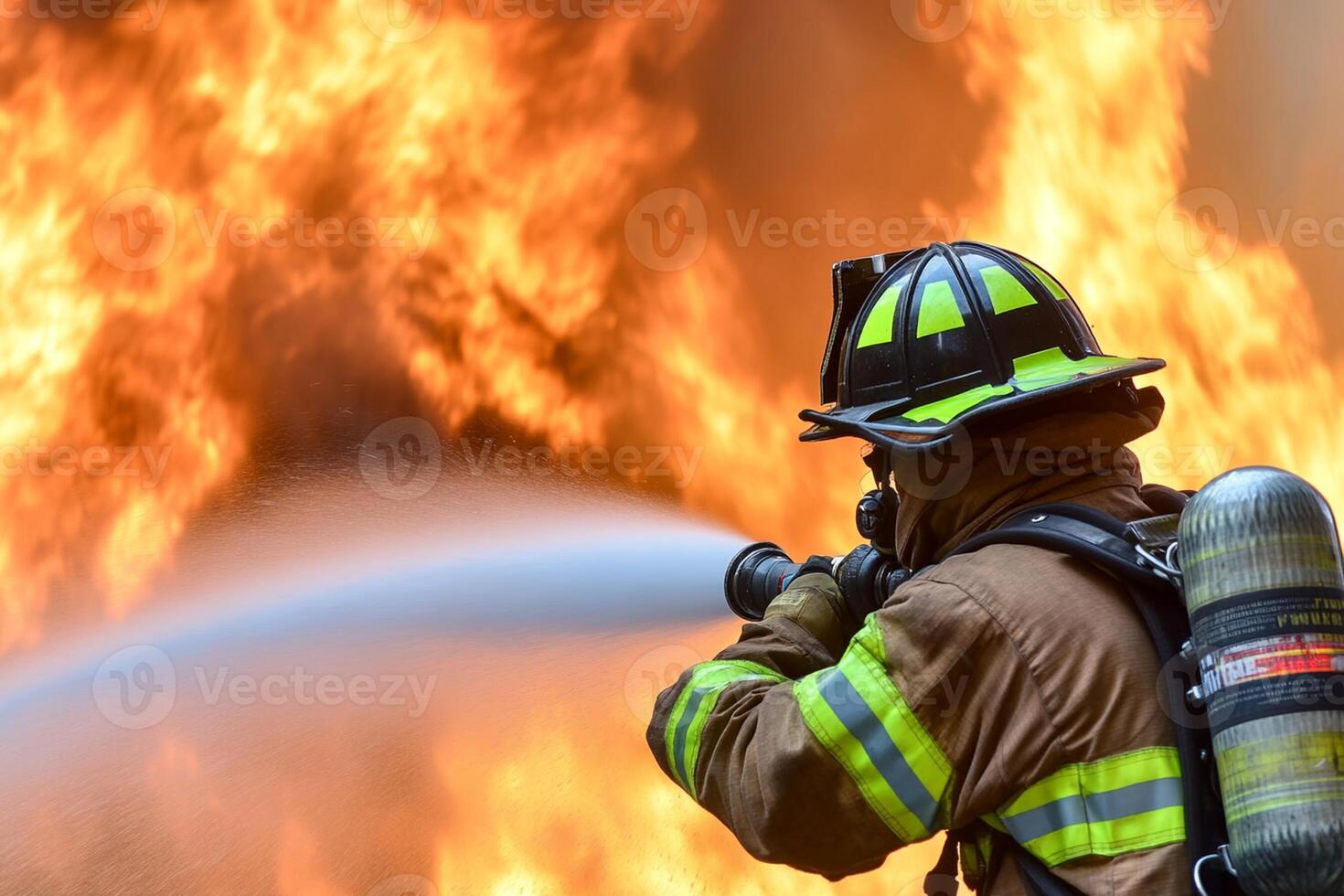 A firefighter is spraying water on a large fire photo