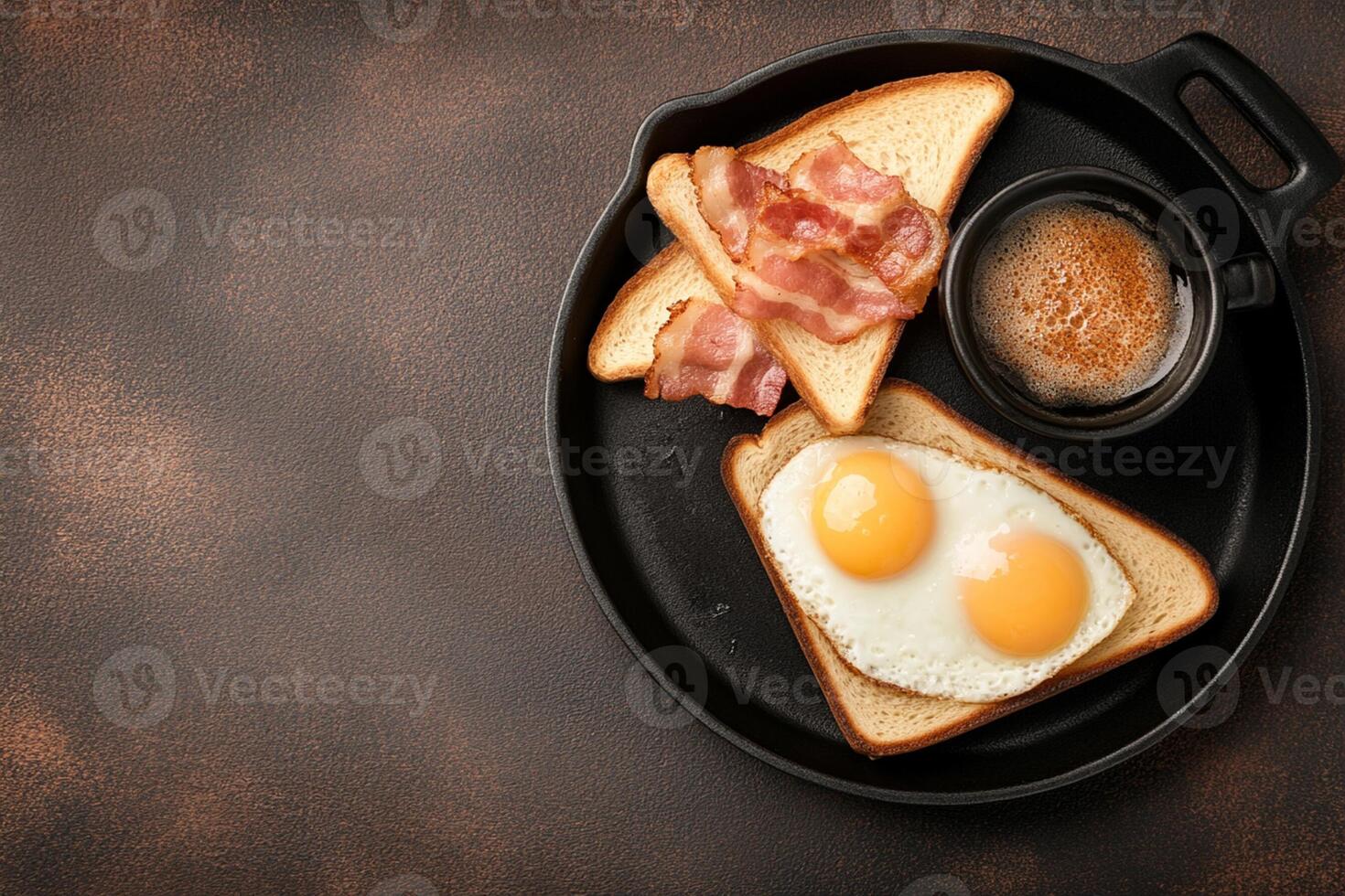 Breakfast with eggs, bacon and toast on a black plate photo