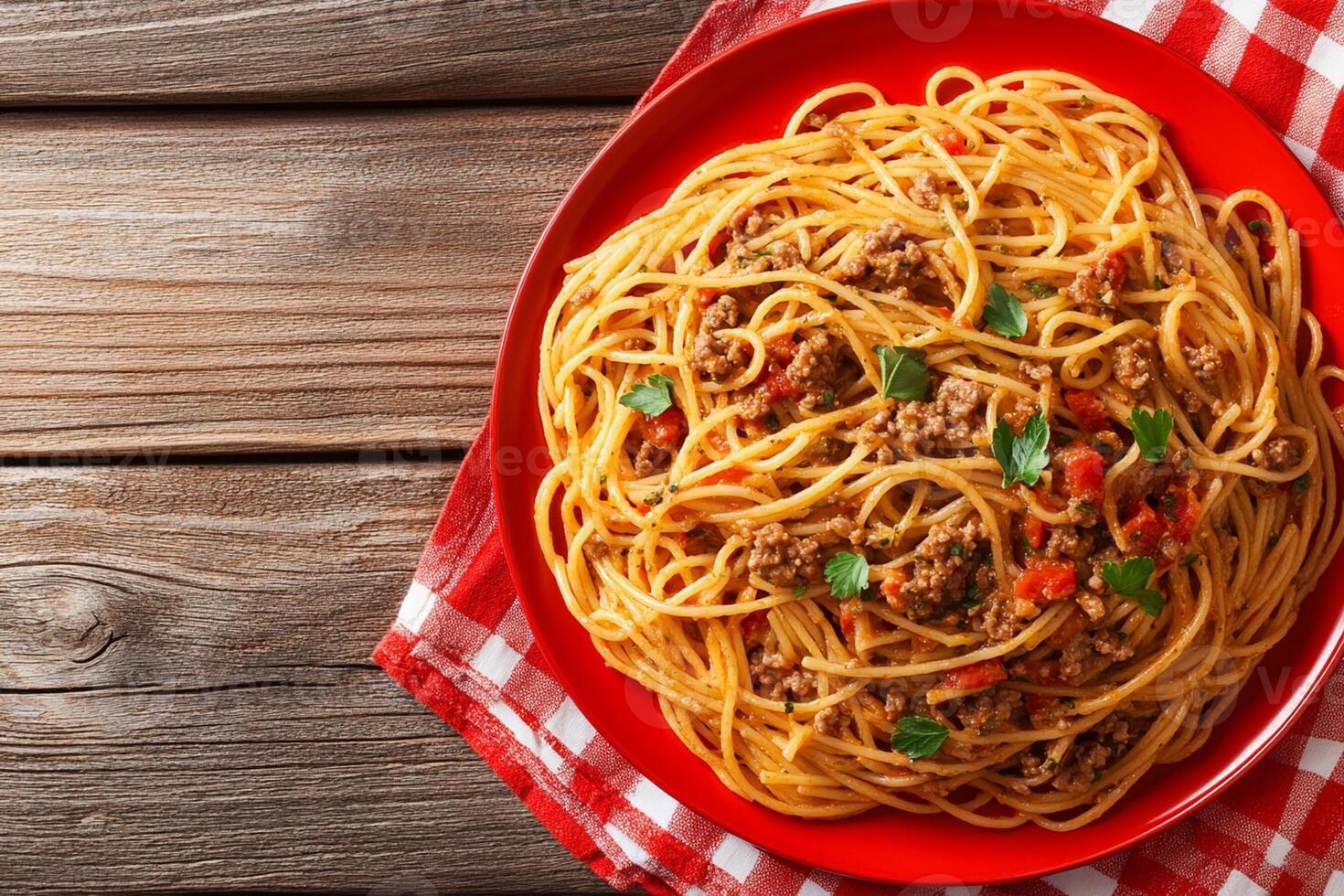 Spaghetti with meat and tomato on a red plate on a wooden table top view photo