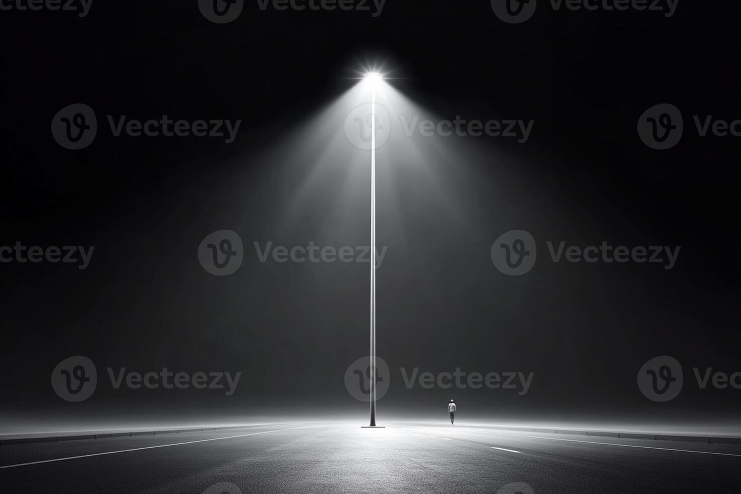 A lone person standing in the middle of a street light photo