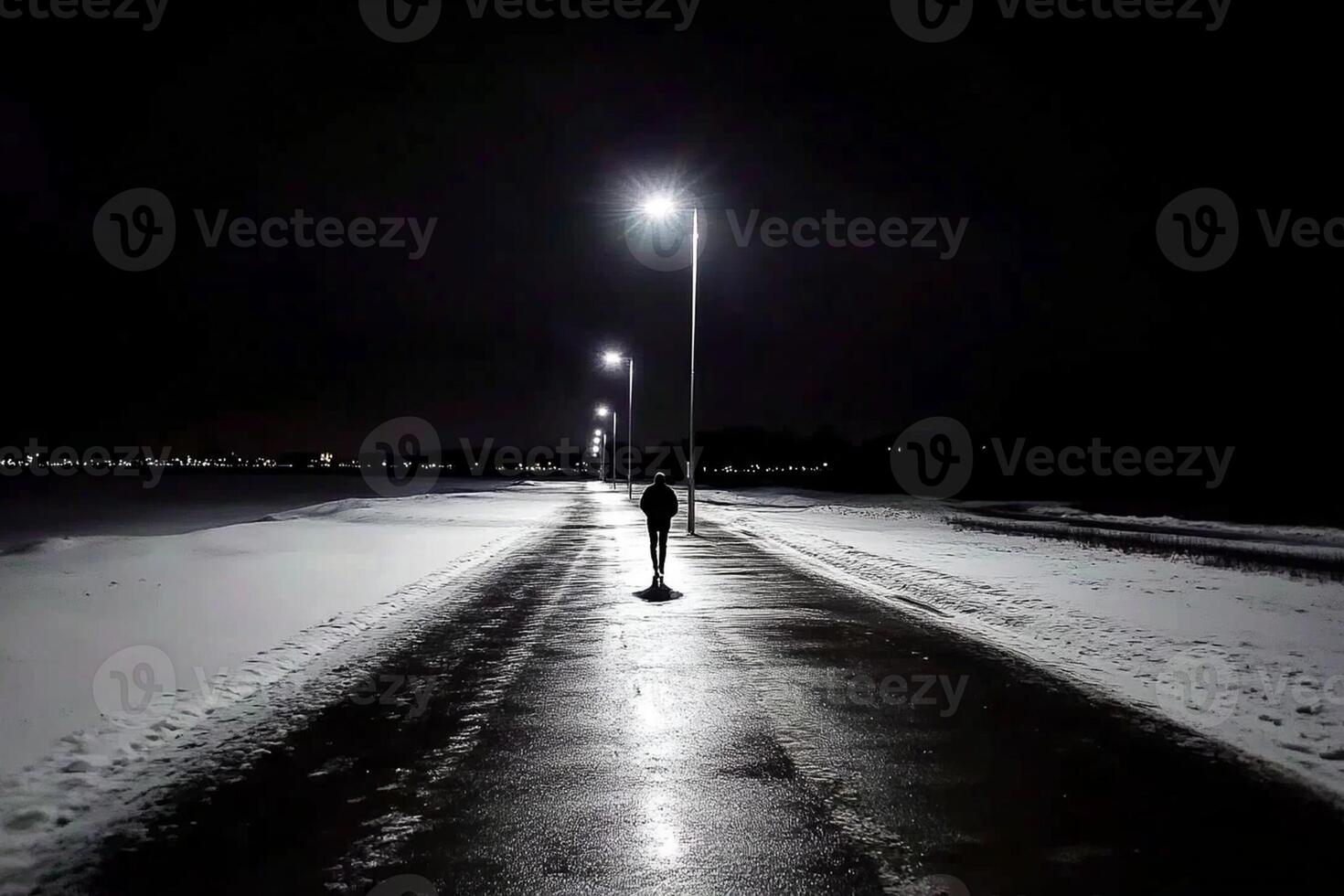 A person walking down a snowy road at night photo