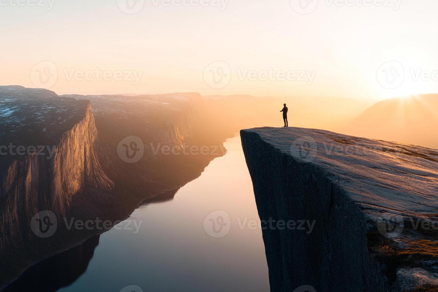 A man standing on the edge of a cliff overlooking a river photo