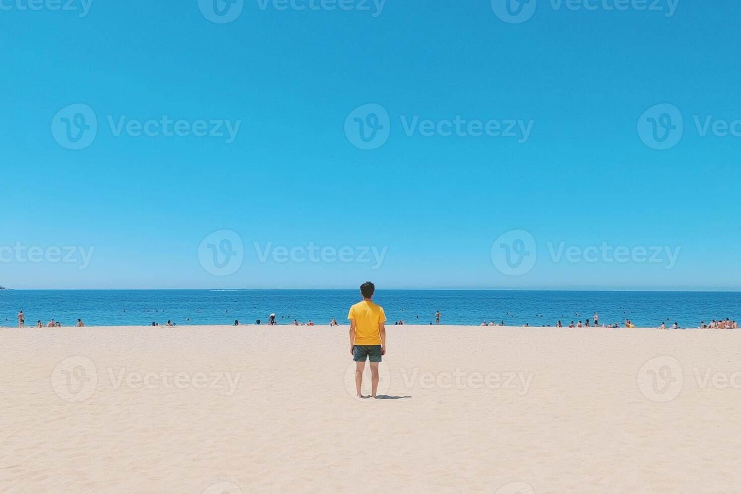 A man standing on the beach looking at the ocean photo