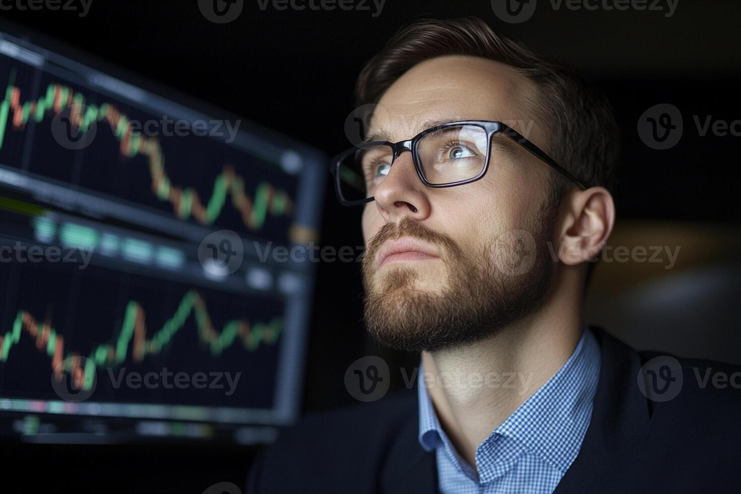 A man in glasses looking at stock market graphs photo