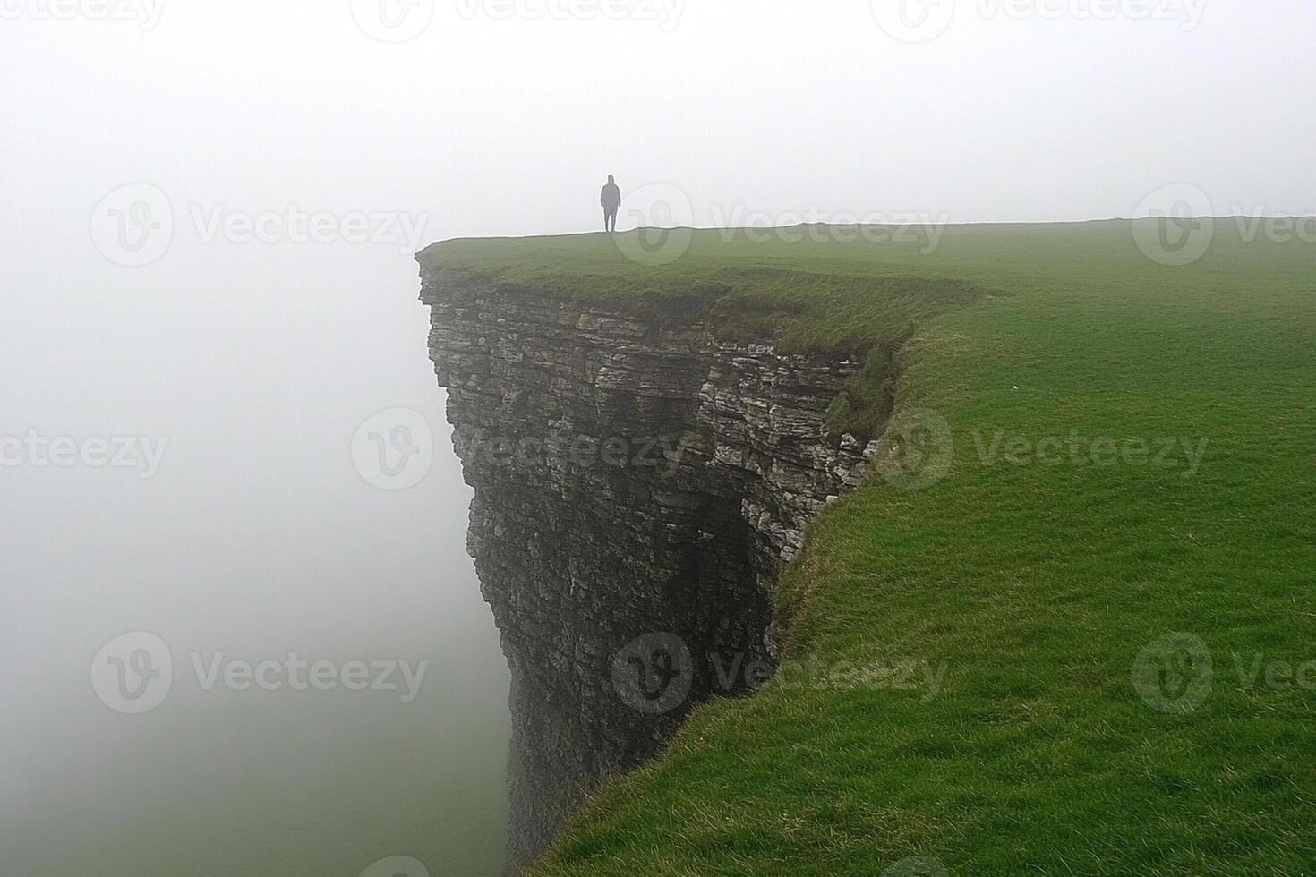 A person standing on top of a cliff in the fog photo