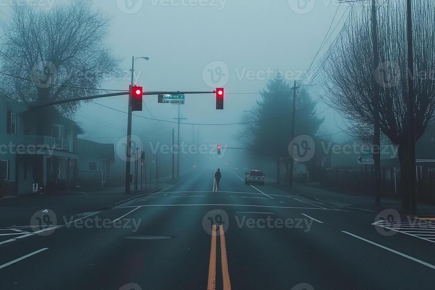 A foggy street with a red light and a person walking across it photo