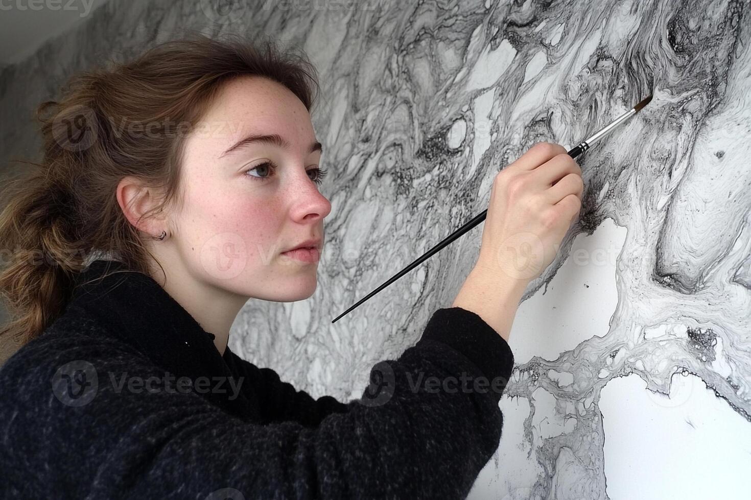 A woman is drawing on a wall with a brush photo