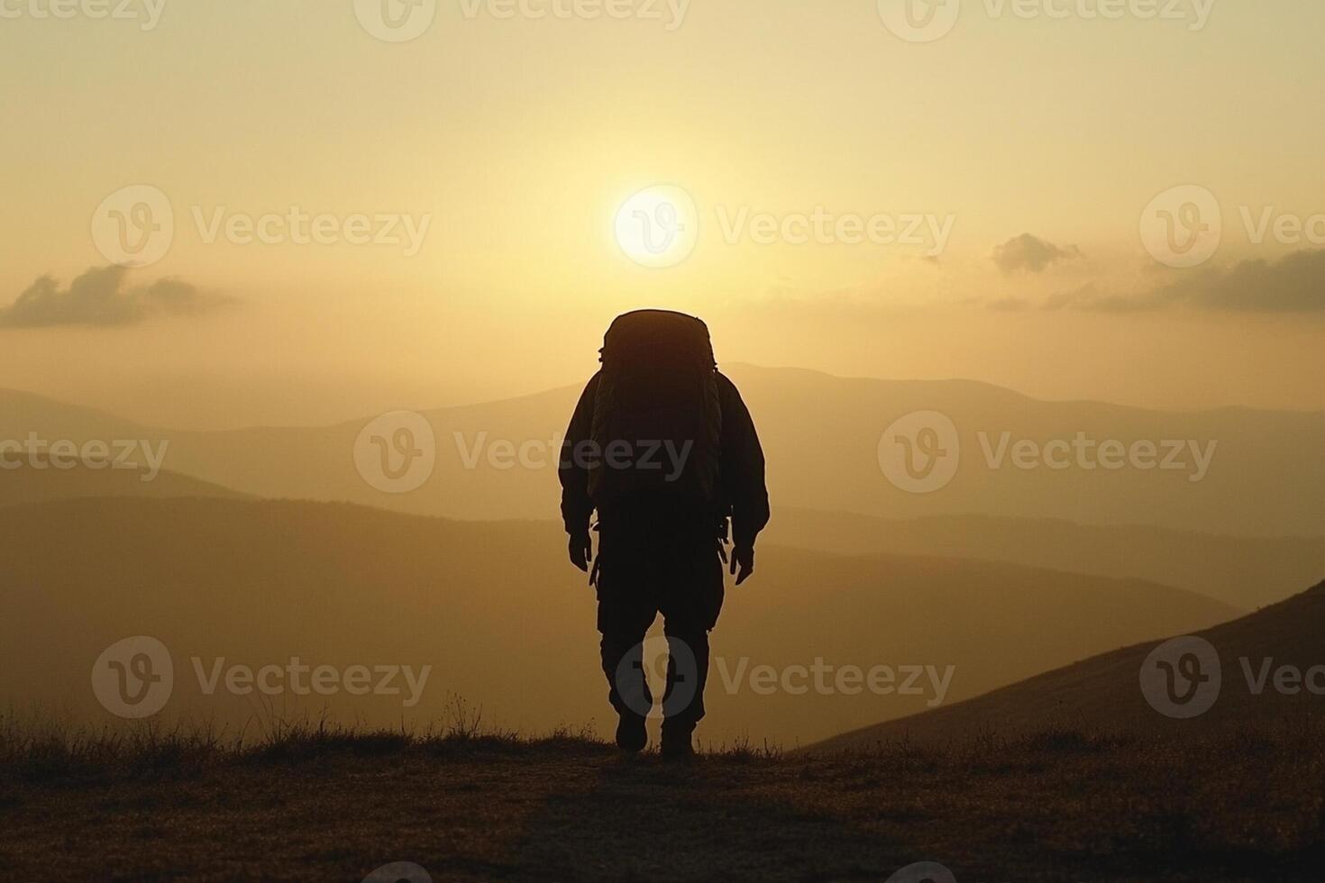 A person with a backpack standing on top of a mountain at sunset photo
