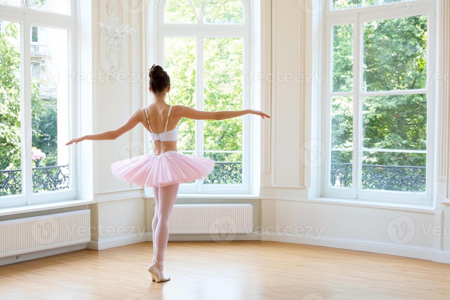 A young ballerina in a pink tutu is standing in front of a large window photo