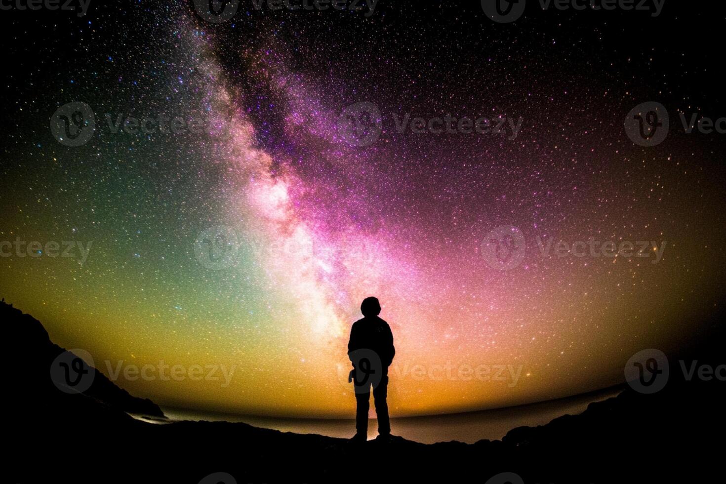 A person standing on a rock looking at the milky way photo