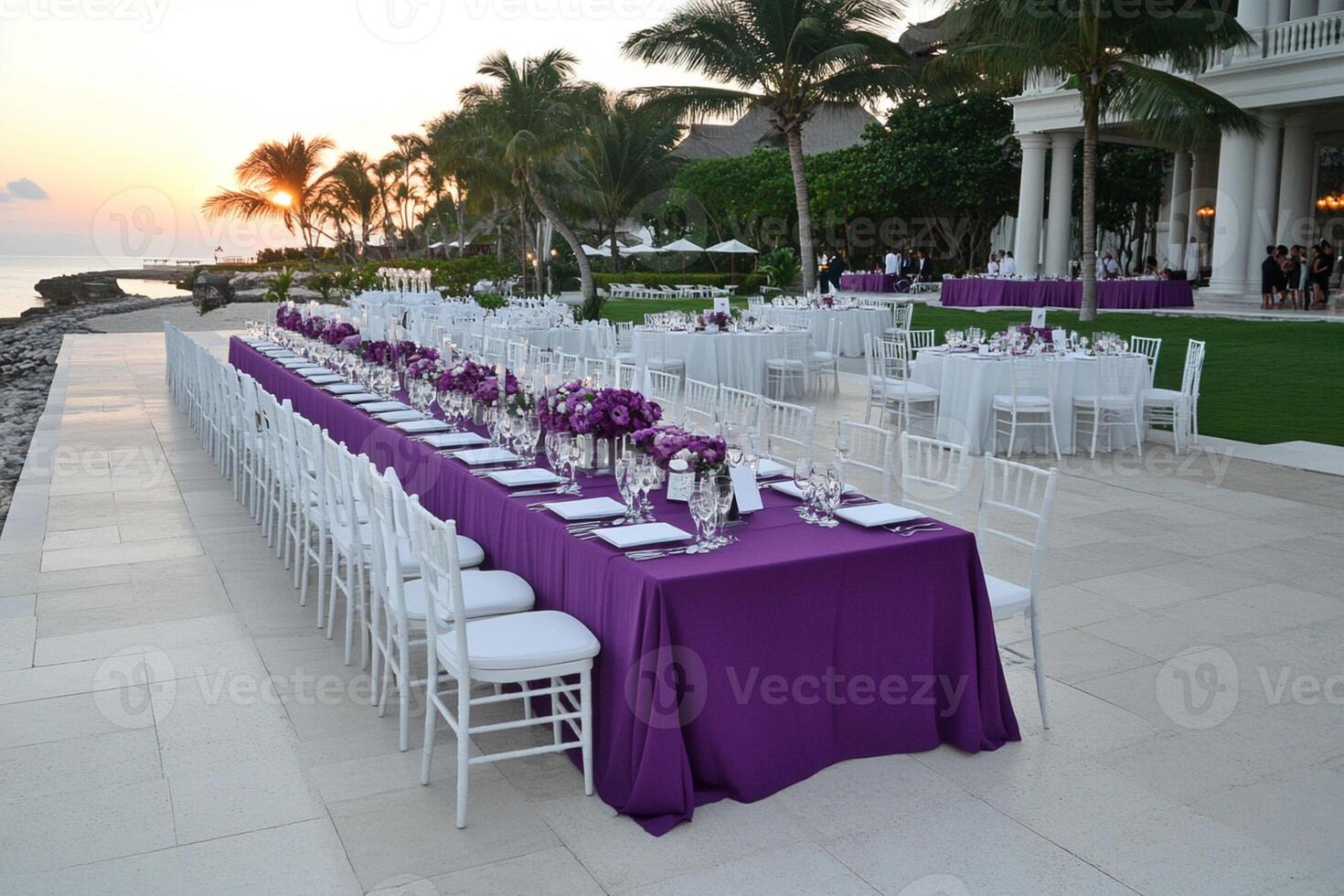 A long table set up with purple cloths and white chairs photo
