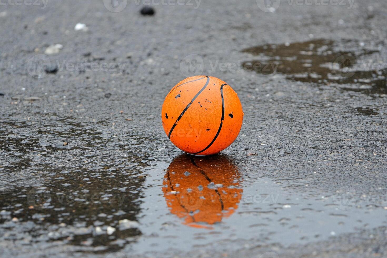 A basketball ball is sitting in a puddle of water photo