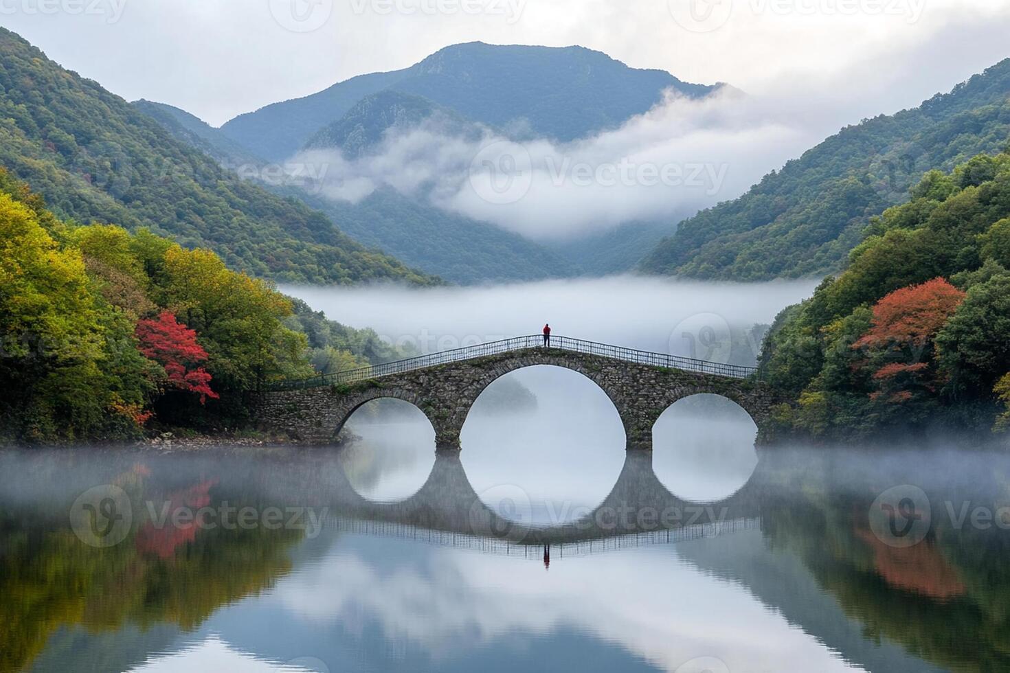 A person standing on a bridge over a river in the mountains photo
