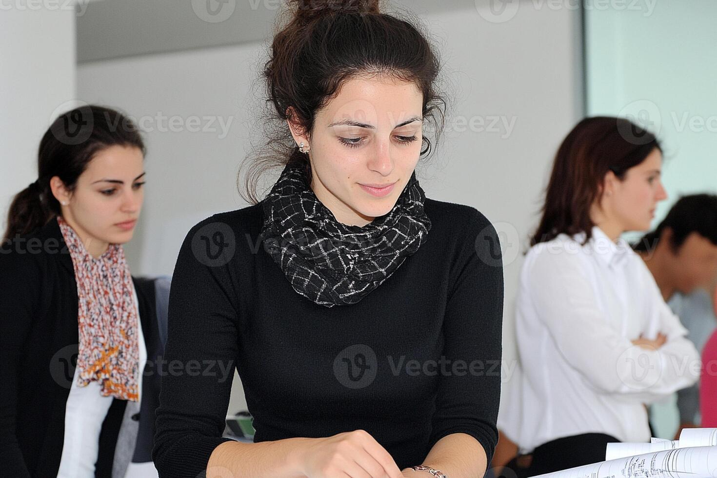 A woman in a black shirt and scarf sitting at a desk photo