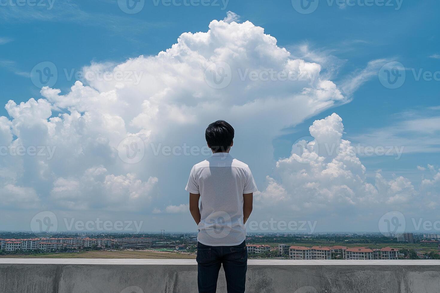 A man standing on a ledge looking at a cloud photo