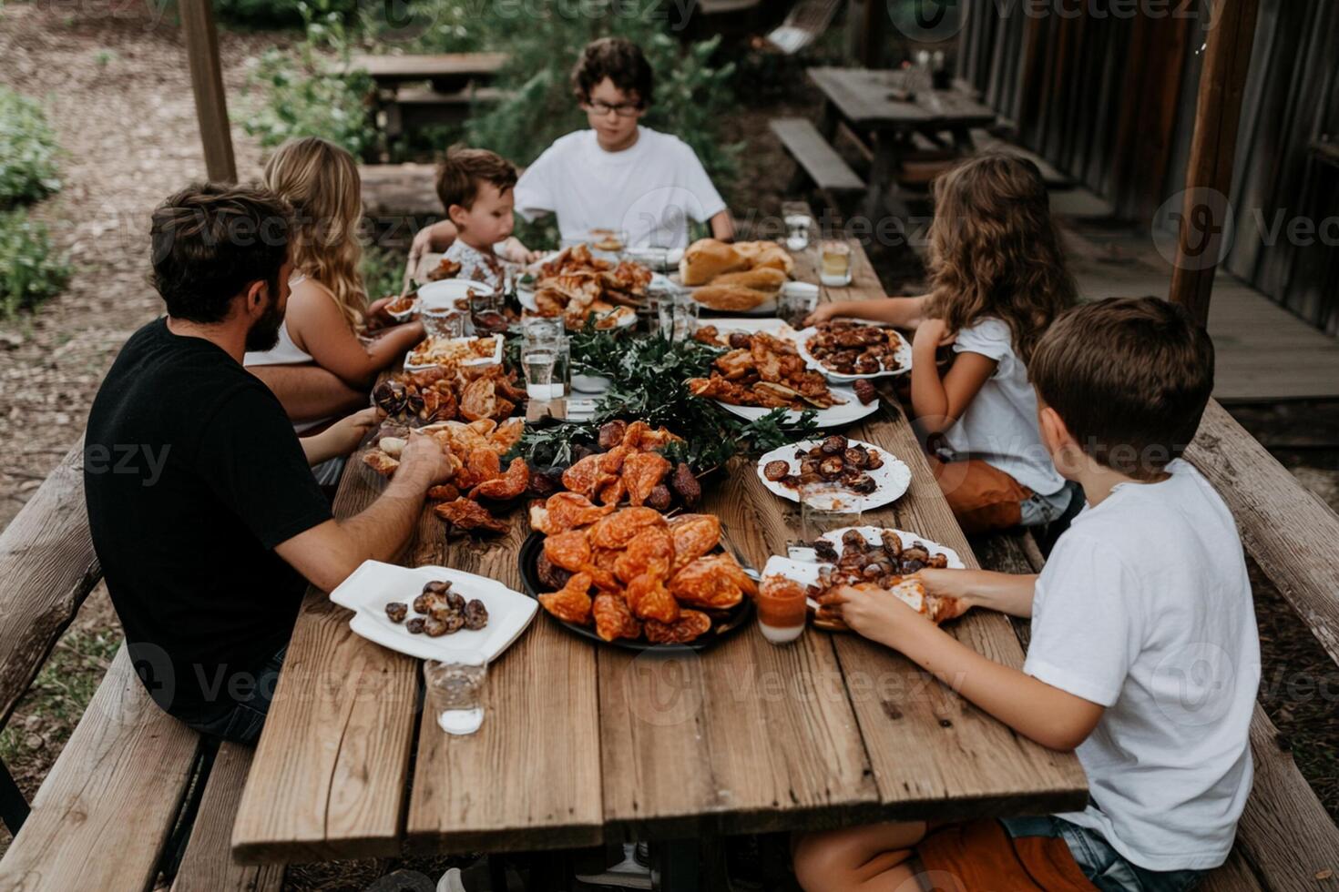 Family eating at outdoor table with food photo