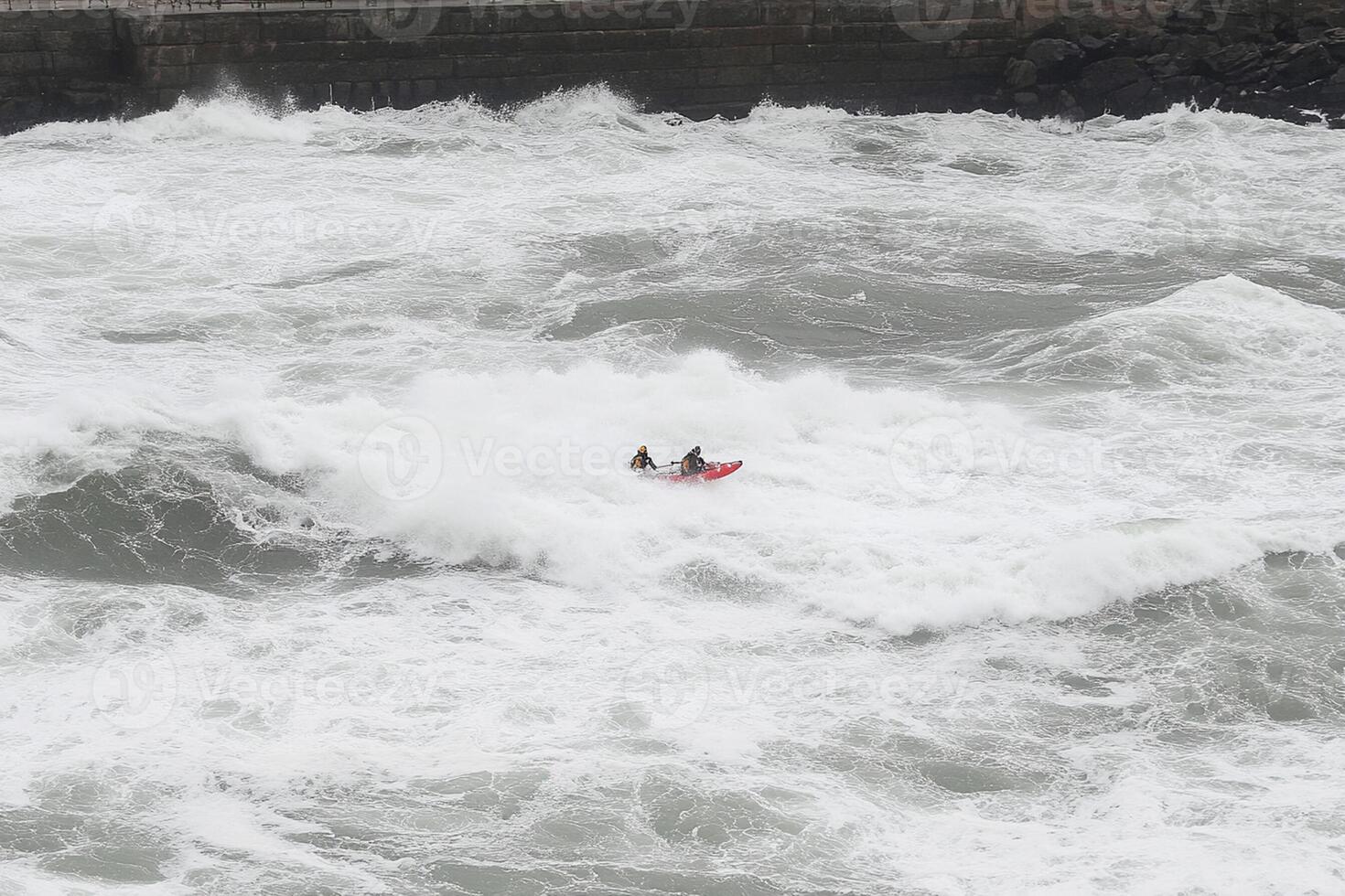 A man in a kayak paddles through rough water photo