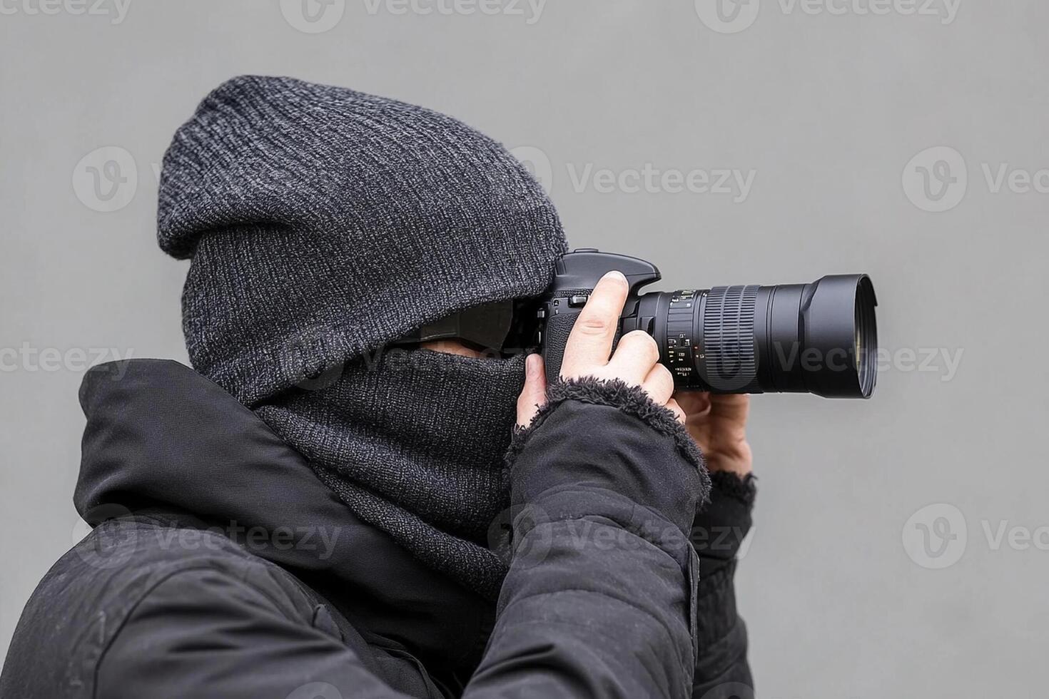 A man wearing a winter hat and a black mask is taking a photo
