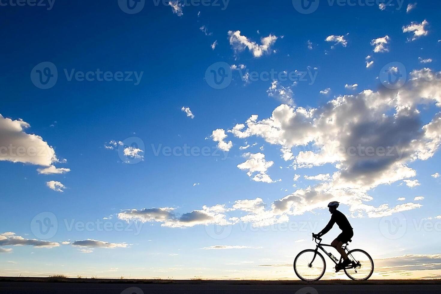A person riding a bike on a road with a blue sky photo